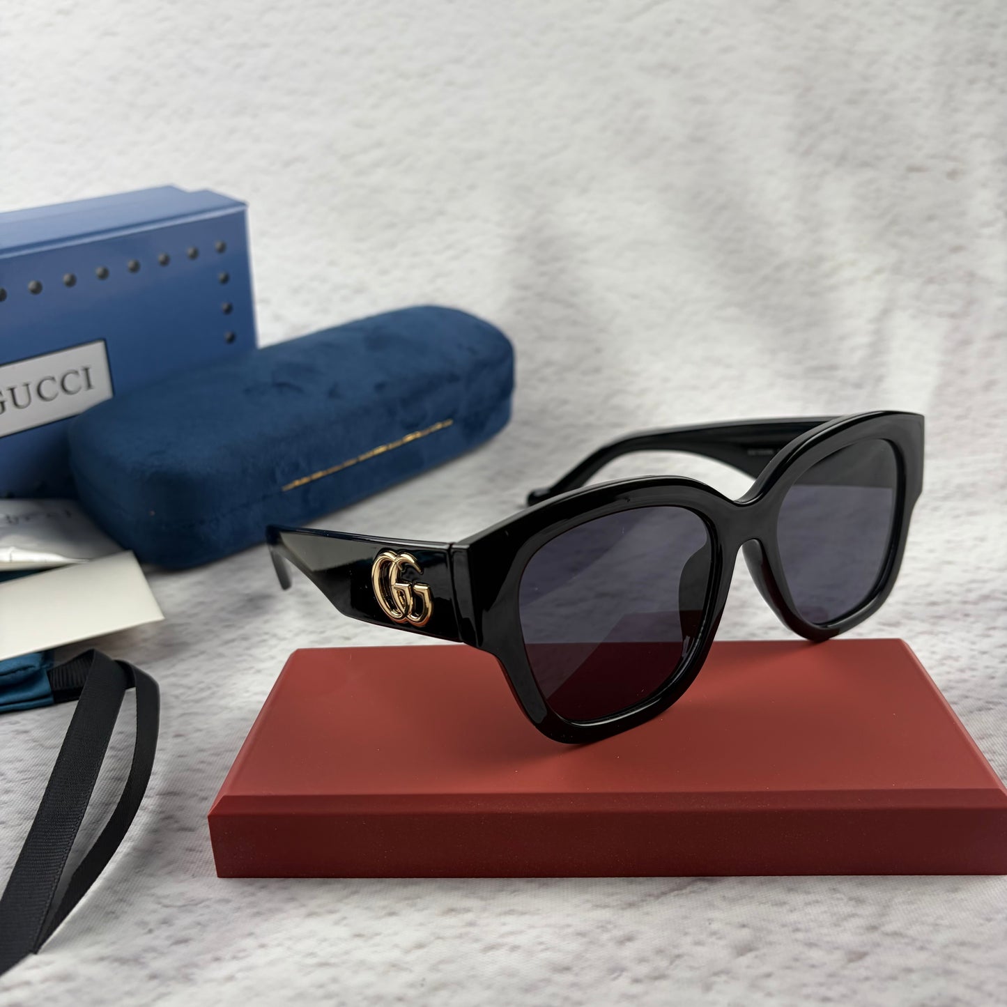 Oversized black frame sunglasses with dark gradient lenses and gold-tone logo detailing on temples.
