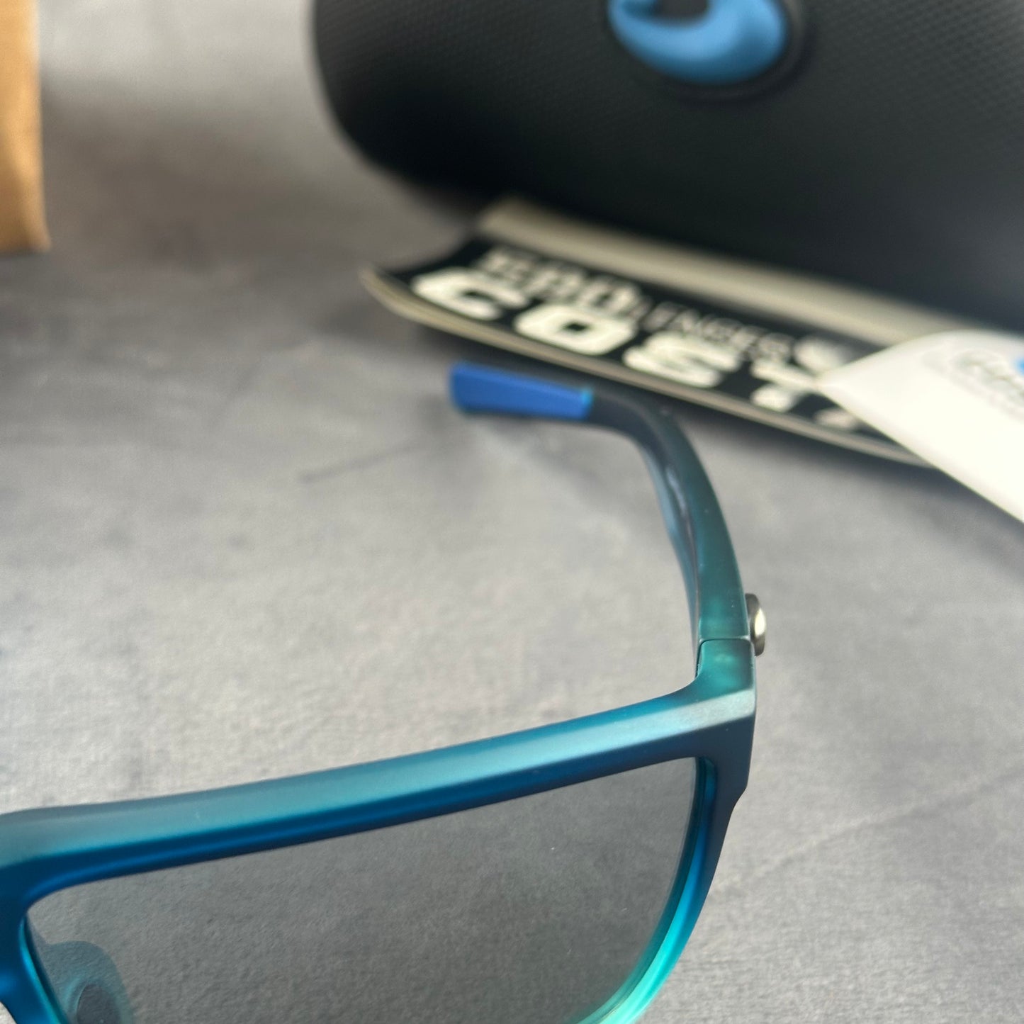 Blue and teal gradient frame sport sunglasses with polarized lenses resting on a blue cloth.