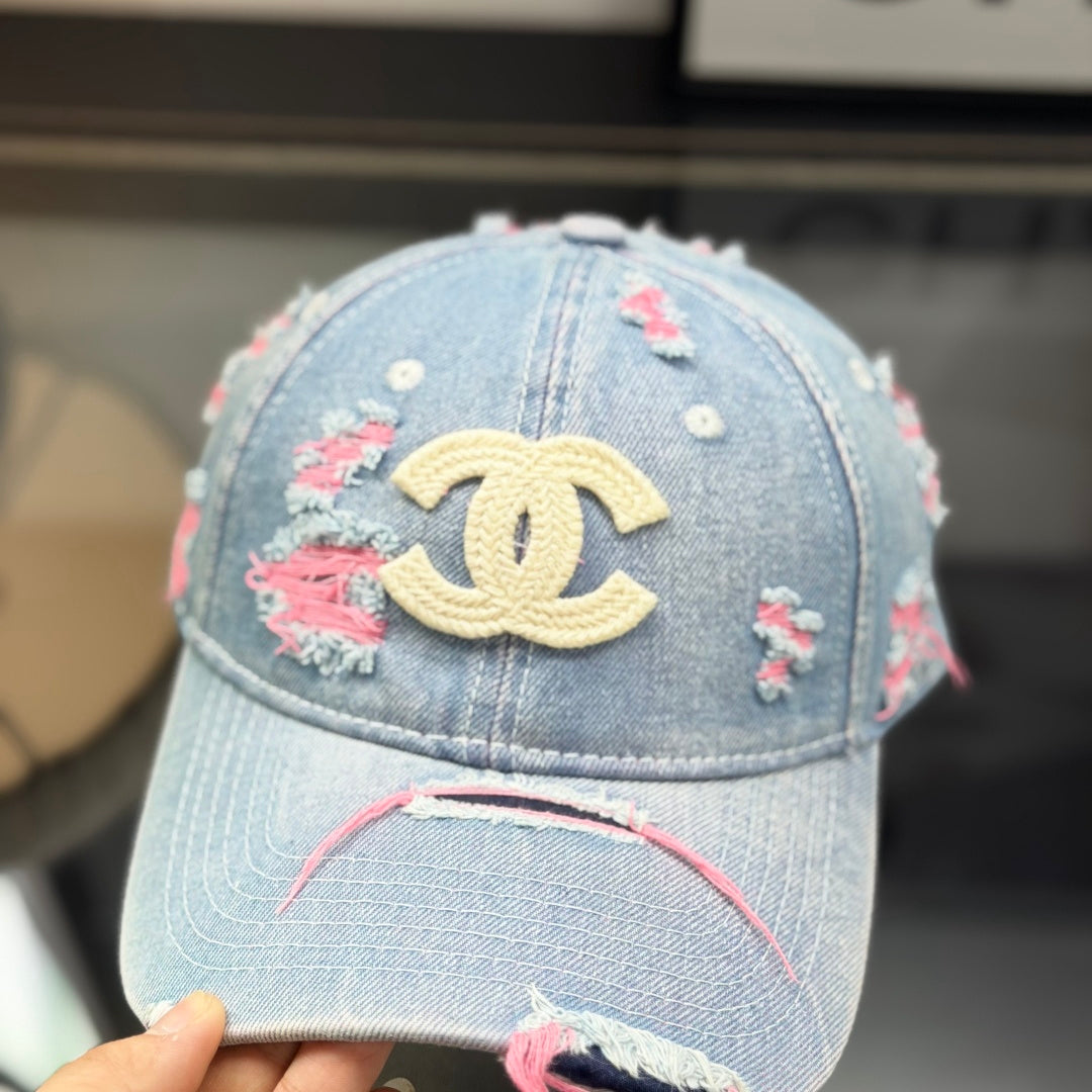 Distressed light wash denim baseball cap with frayed pink stitching and embroidery on the front.