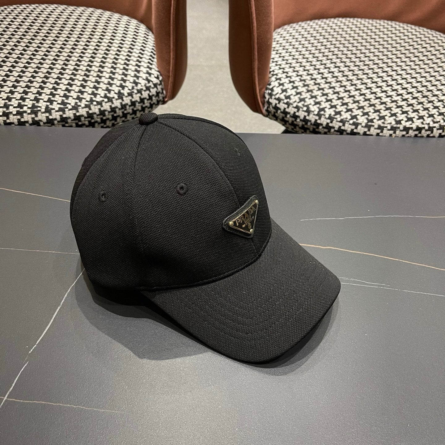 A black premium structured baseball cap with a centered metal triangular emblem on the front.