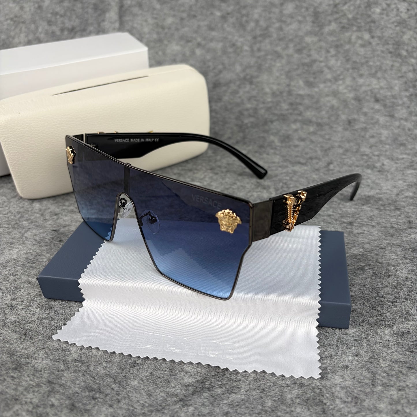 Oversized shield sunglasses with gradient blue lenses and gold metallic accents on the side arms.