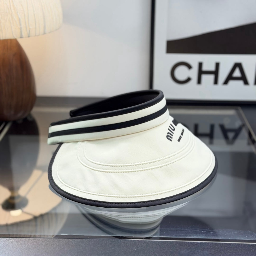 A stylish off-white open-top sports visor with black trim and embroidered text detailing.