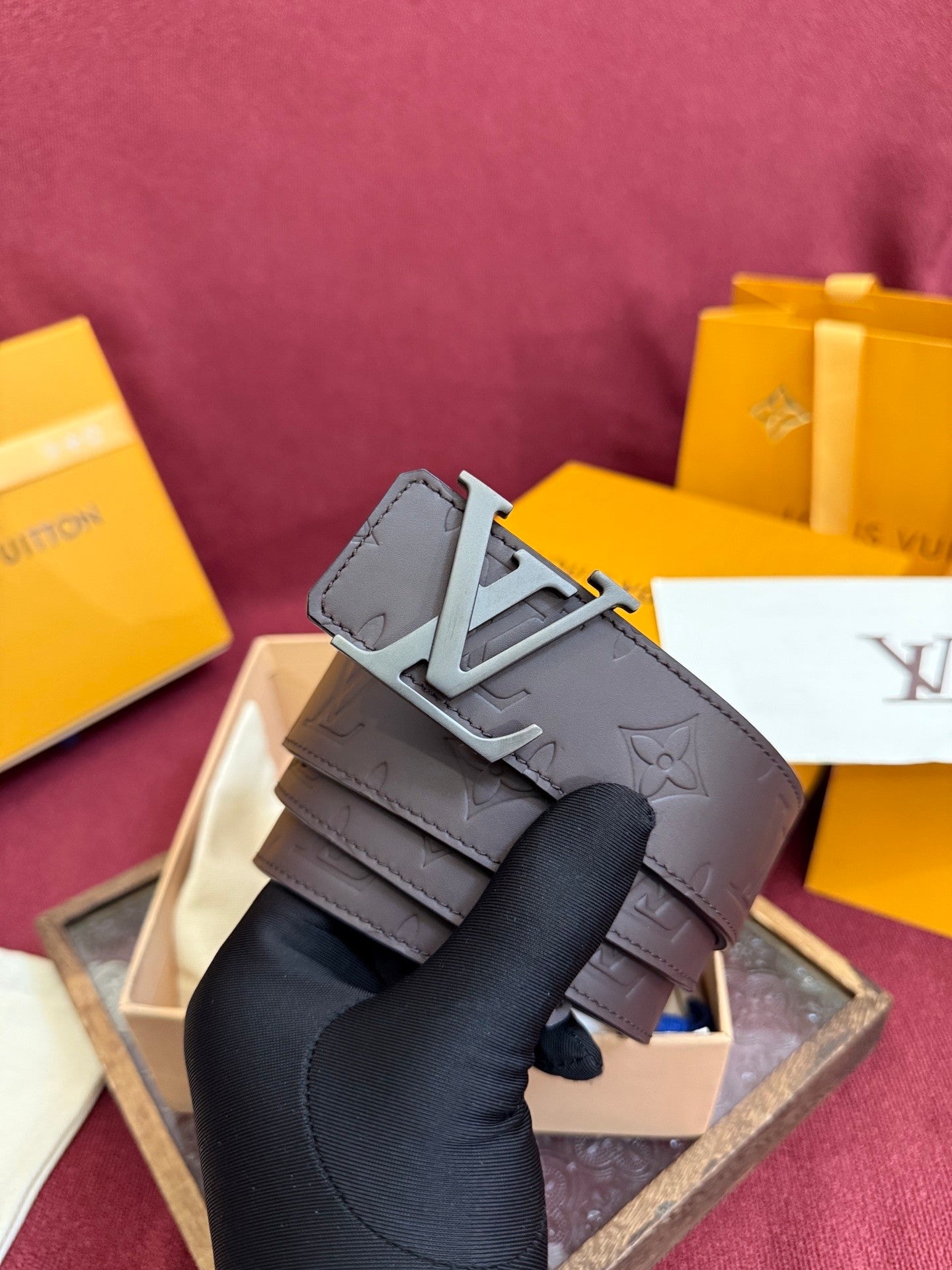 Close-up of a brown embossed leather belt featuring a matte metal buckle and patterned surface.