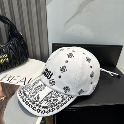 White cotton baseball cap with black paisley patterns and an adjustable drawstring back closure.