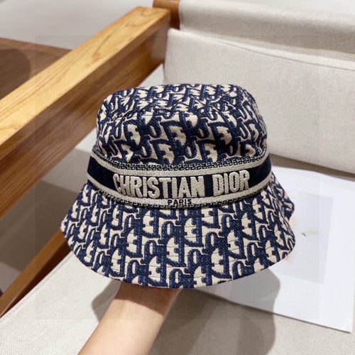 Close-up of a blue and beige monogram patterned cotton bucket hat with a wide brim and fabric band.