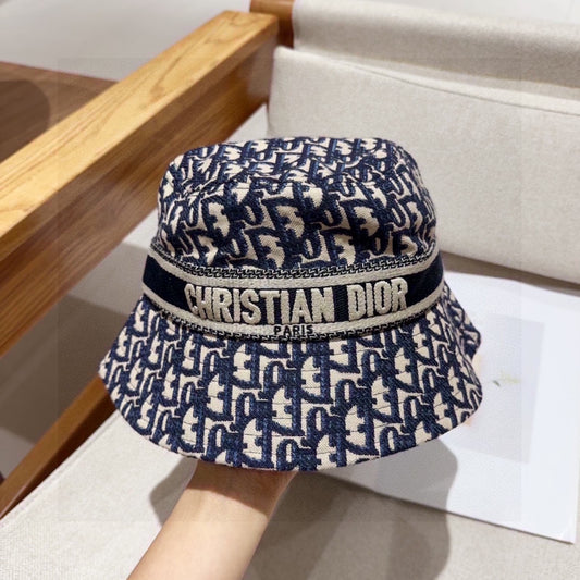 Close-up of a blue and beige monogram patterned cotton bucket hat with a wide brim and fabric band.
