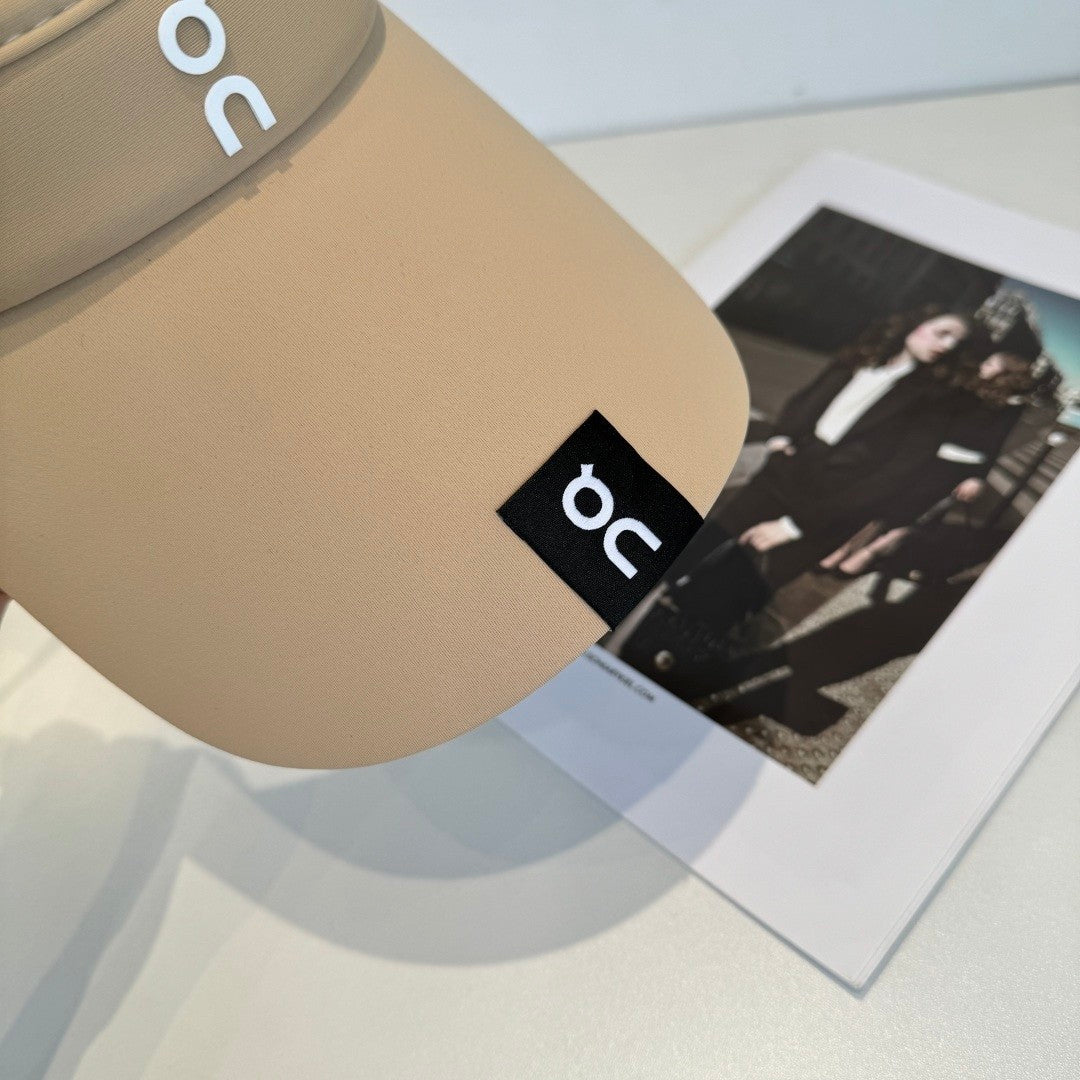 A beige lightweight sport visor with adjustable elastic band, featuring a minimalist logo design.