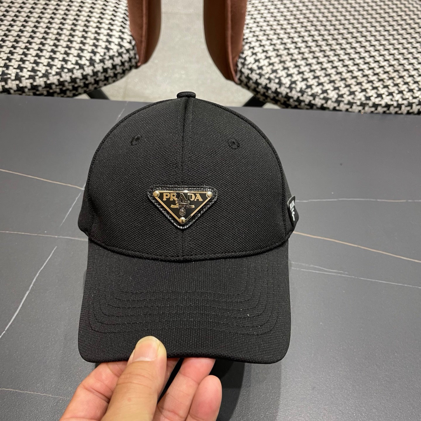 A black premium structured baseball cap with a centered metal triangular emblem on the front.