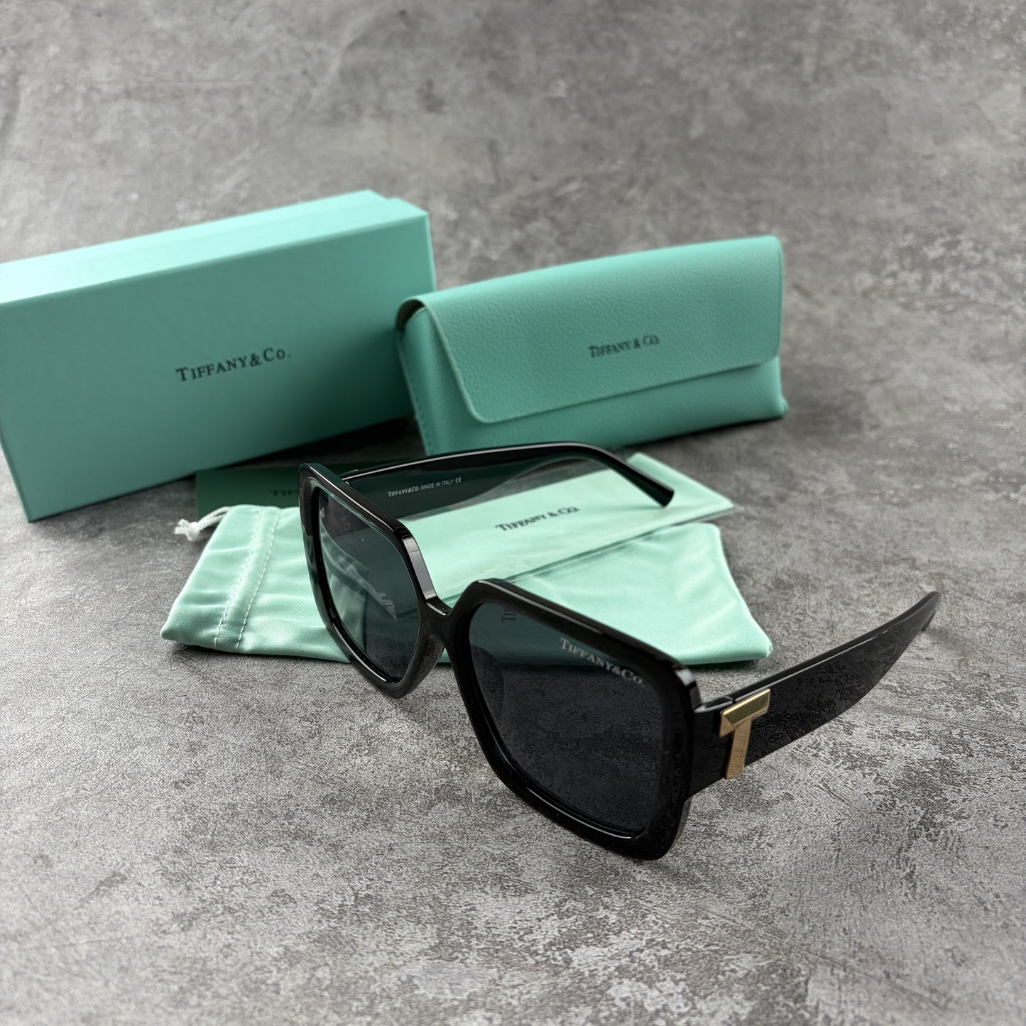 Oversized black square sunglasses with metallic side detailing, displayed with a storage case.
