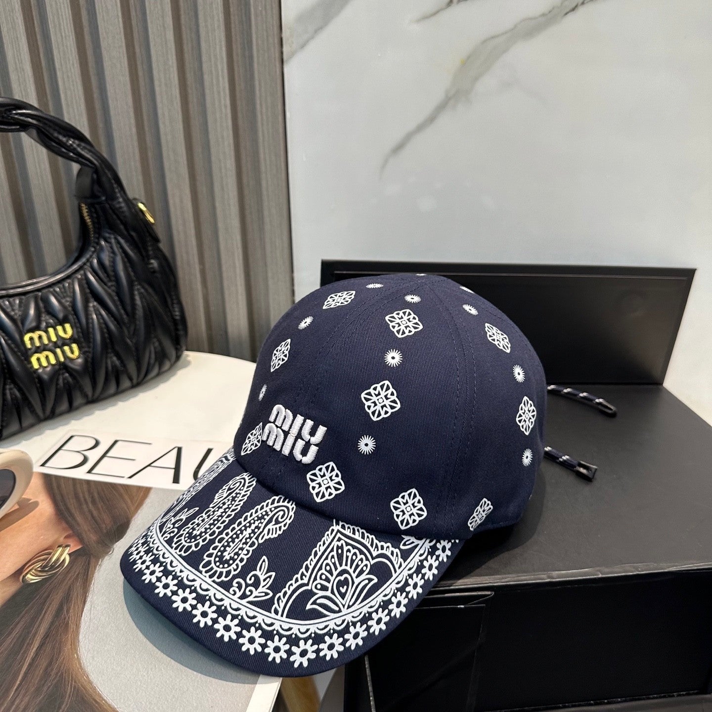 Navy blue baseball cap with white embroidered paisley patterns and an adjustable back strap.
