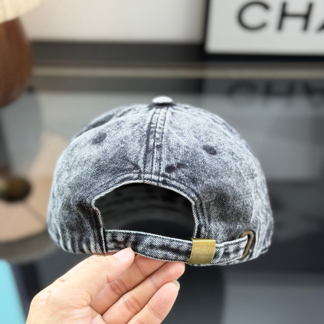 A grey distressed washed denim baseball cap with an embroidered patch on the front panel.