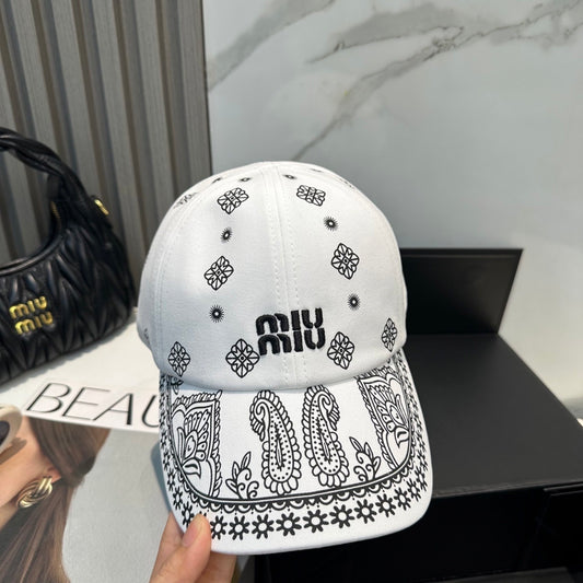 White cotton baseball cap with black paisley patterns and an adjustable drawstring back closure.