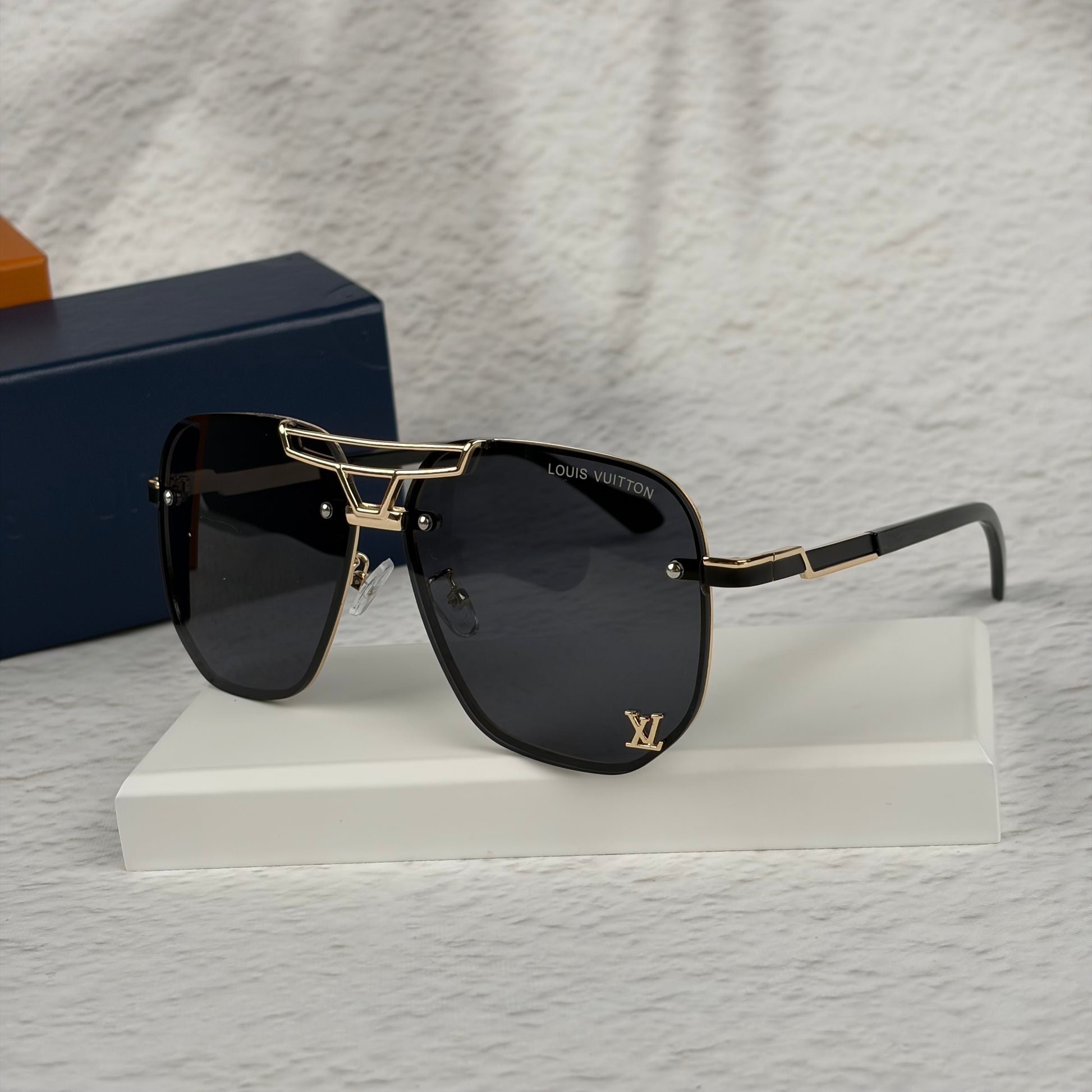 Modern aviator sunglasses with gold metal bridge, dark lenses, and black temple tips on display.