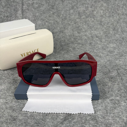 Oversized bold red shield sunglasses with dark lenses on a grey background with a white case.