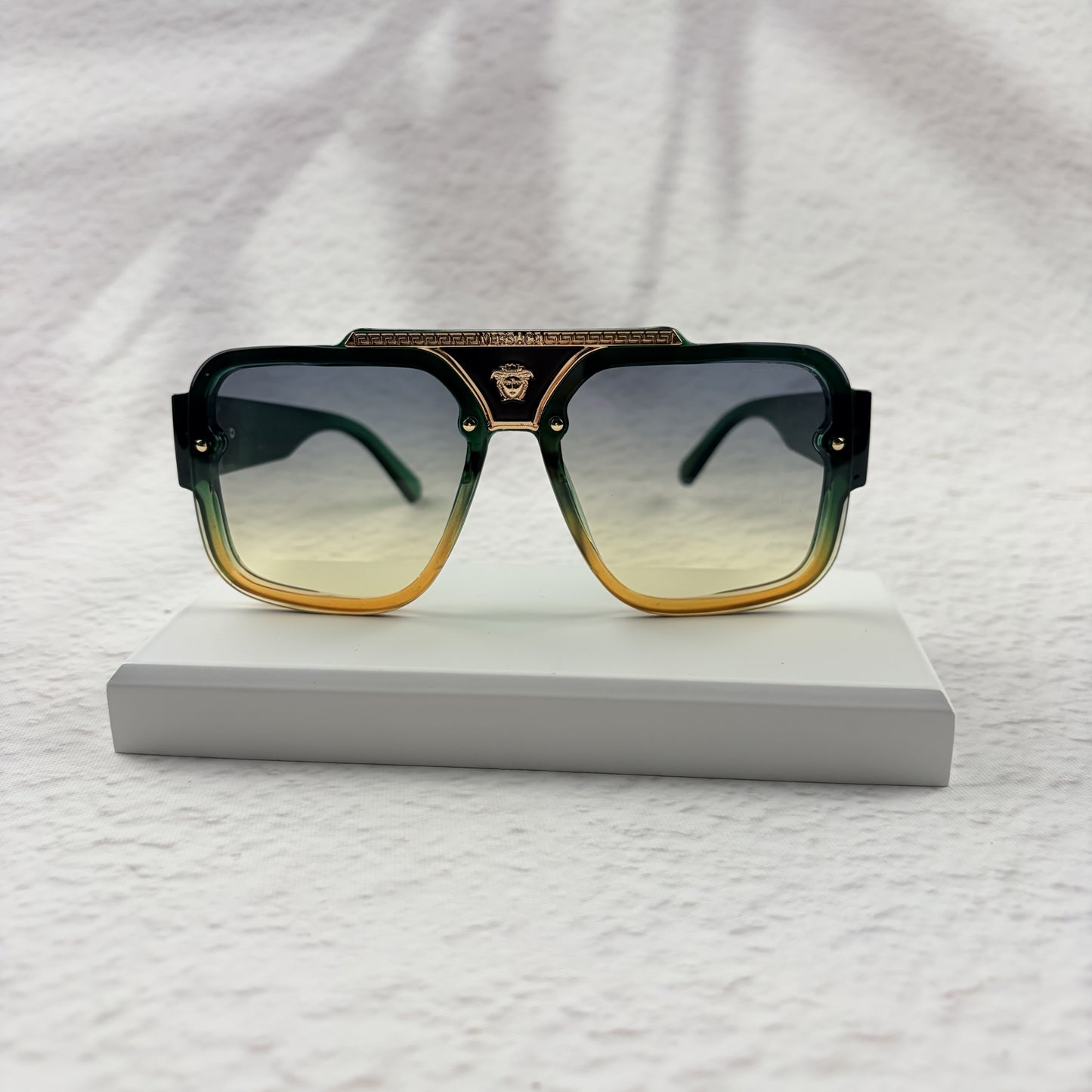 Oversized geometric sunglasses with green-to-yellow gradient lenses and gold metallic frame details.