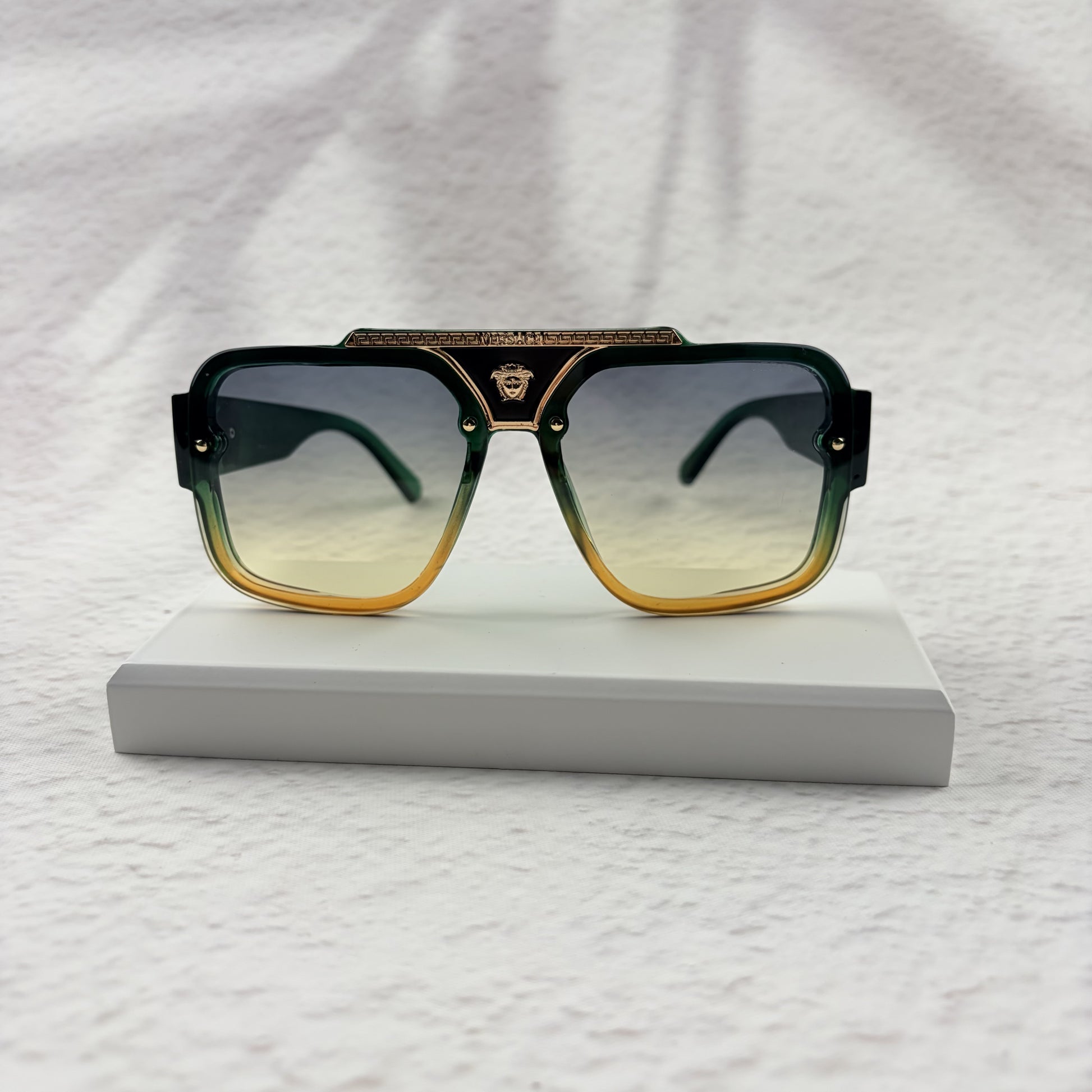 Oversized geometric sunglasses with green-to-yellow gradient lenses and gold metallic frame details.