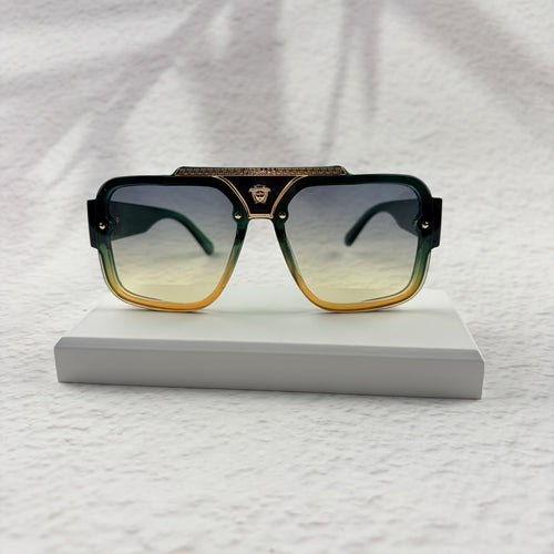 Oversized geometric sunglasses with green-to-yellow gradient lenses and gold metallic frame details.