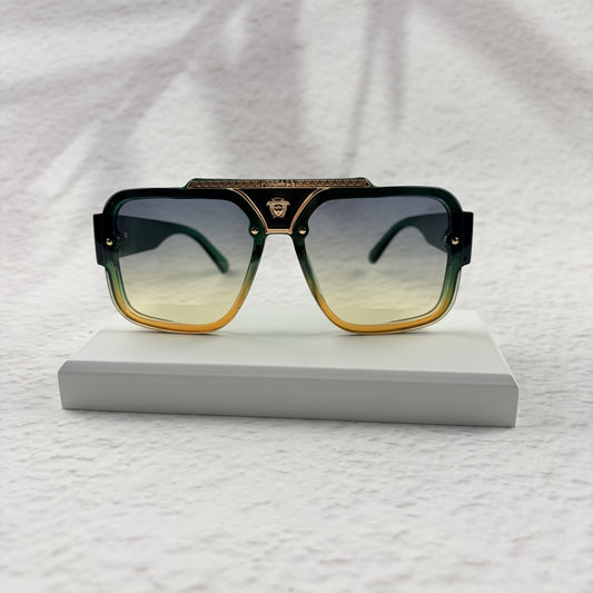 Oversized geometric sunglasses with green-to-yellow gradient lenses and gold metallic frame details.