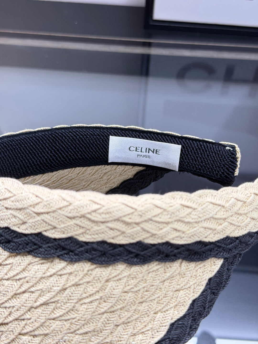 Woven straw sun visor with black contrast trim and decorative logo detail for summer protection.