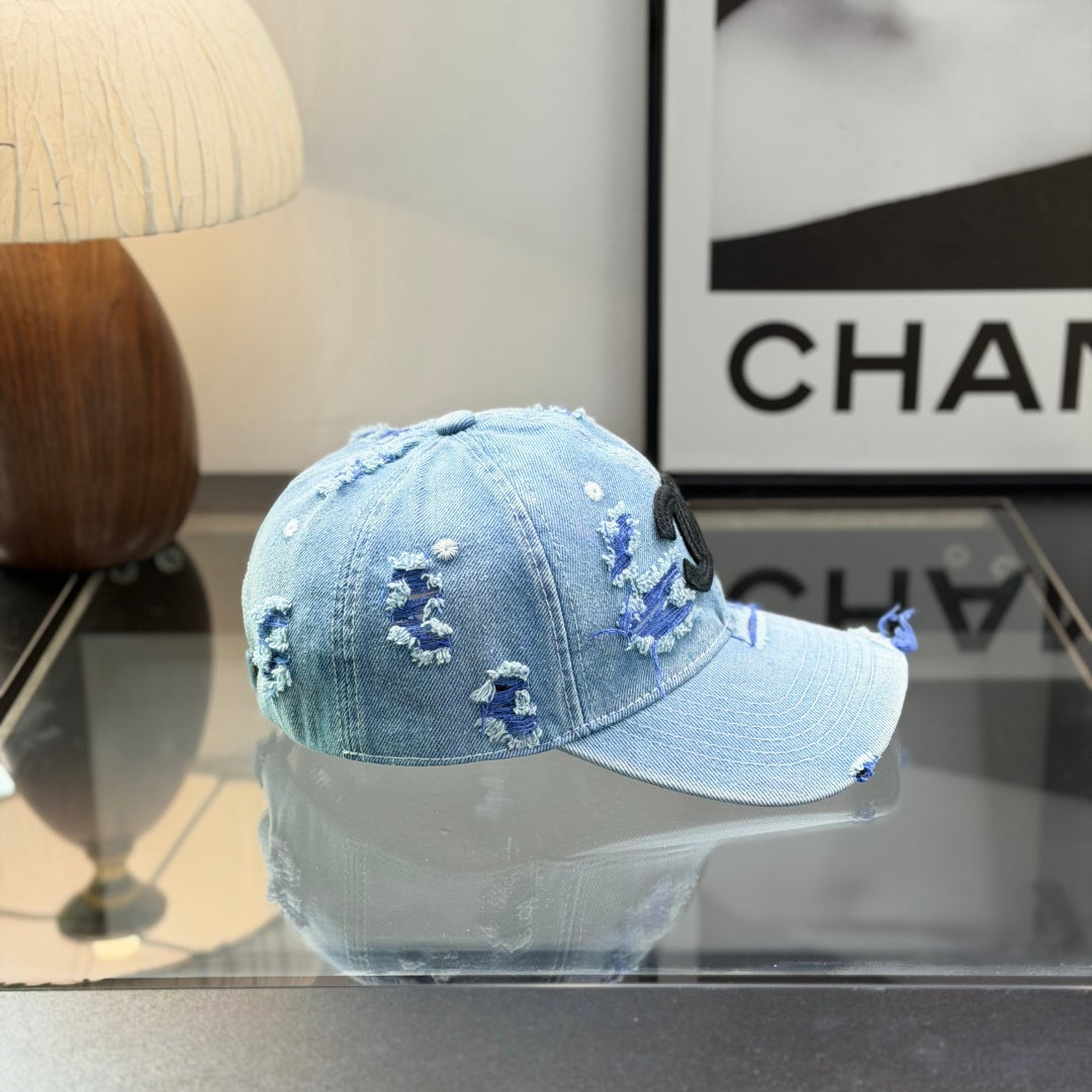 Distressed light wash denim baseball cap with frayed edges and embroidered front emblem.