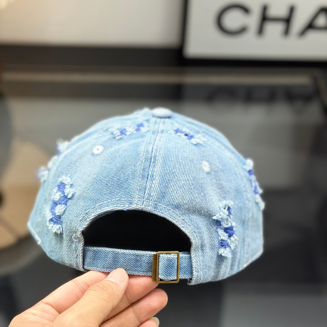 Distressed light wash denim baseball cap with frayed edges and embroidered front emblem.