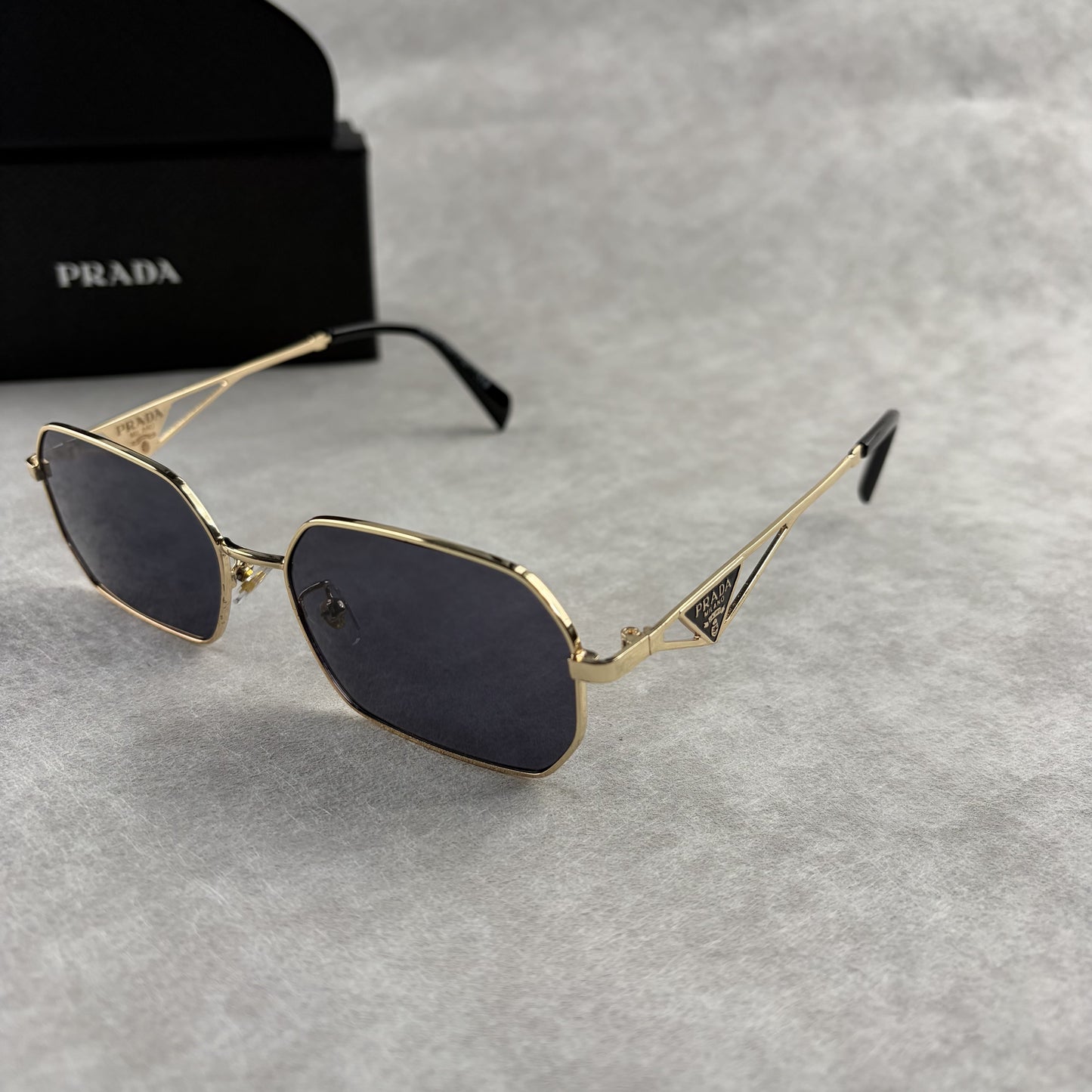 Geometric metal-frame sunglasses in gold tone with dark smoke lenses and signature triangular temple