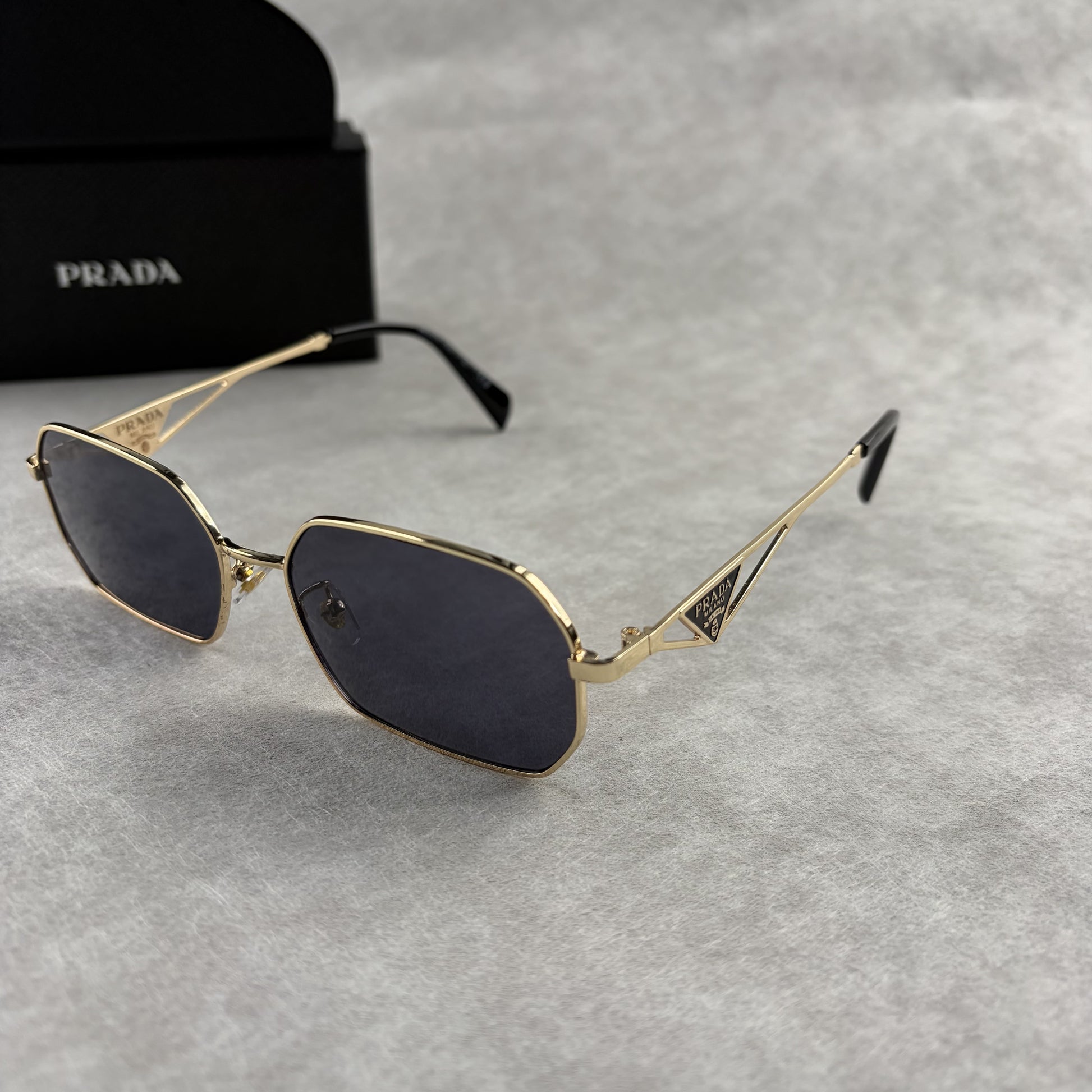 Geometric metal-frame sunglasses in gold tone with dark smoke lenses and signature triangular temple