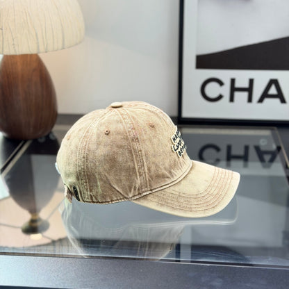Vintage style distressed light brown denim baseball cap with embroidered letter patch on front.