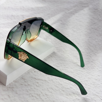 Oversized geometric sunglasses with green-to-yellow gradient lenses and gold metallic frame details.