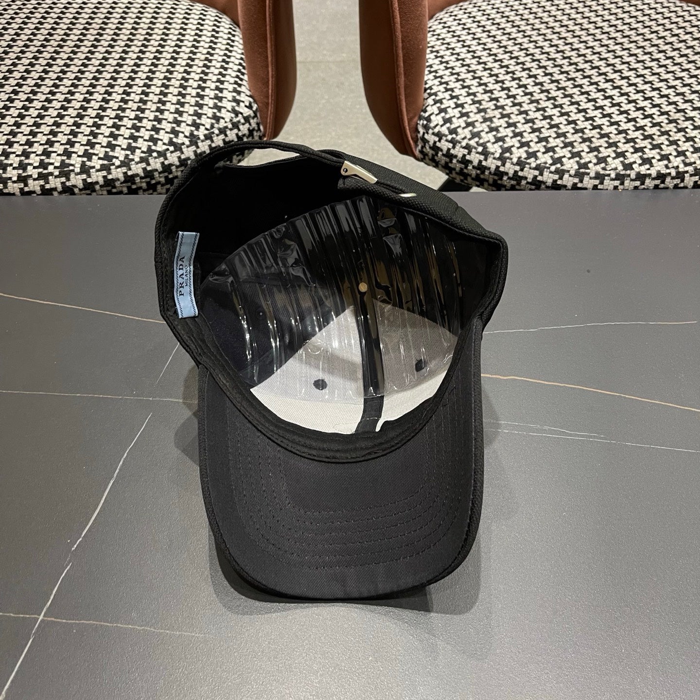 A black premium structured baseball cap with a centered metal triangular emblem on the front.