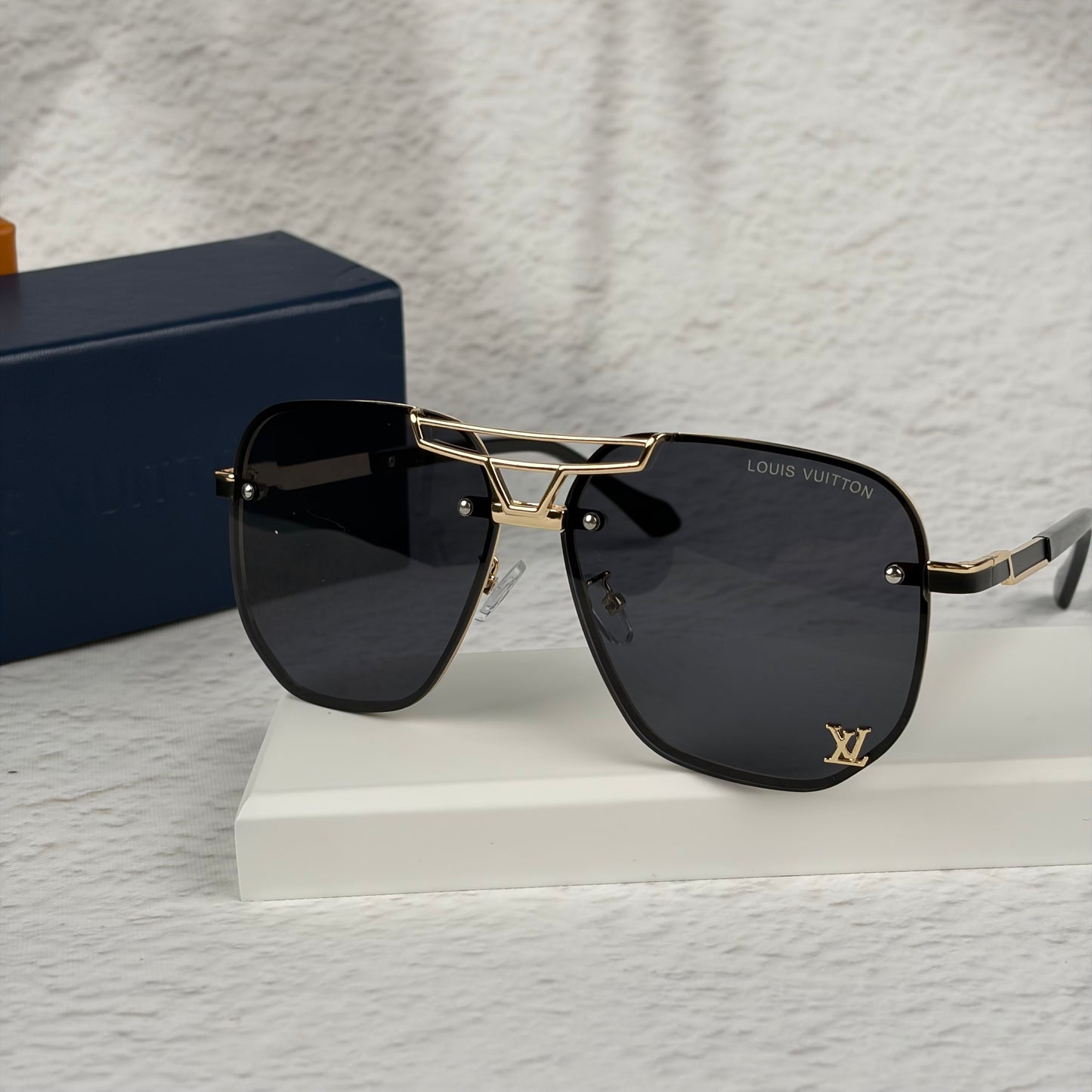 Modern aviator sunglasses with gold metal bridge, dark lenses, and black temple tips on display.