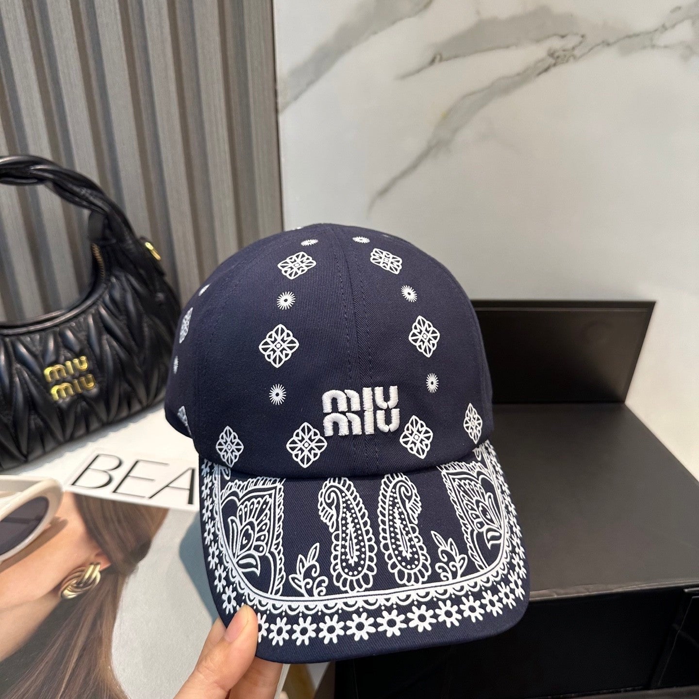 Navy blue baseball cap with white embroidered paisley patterns and an adjustable back strap.