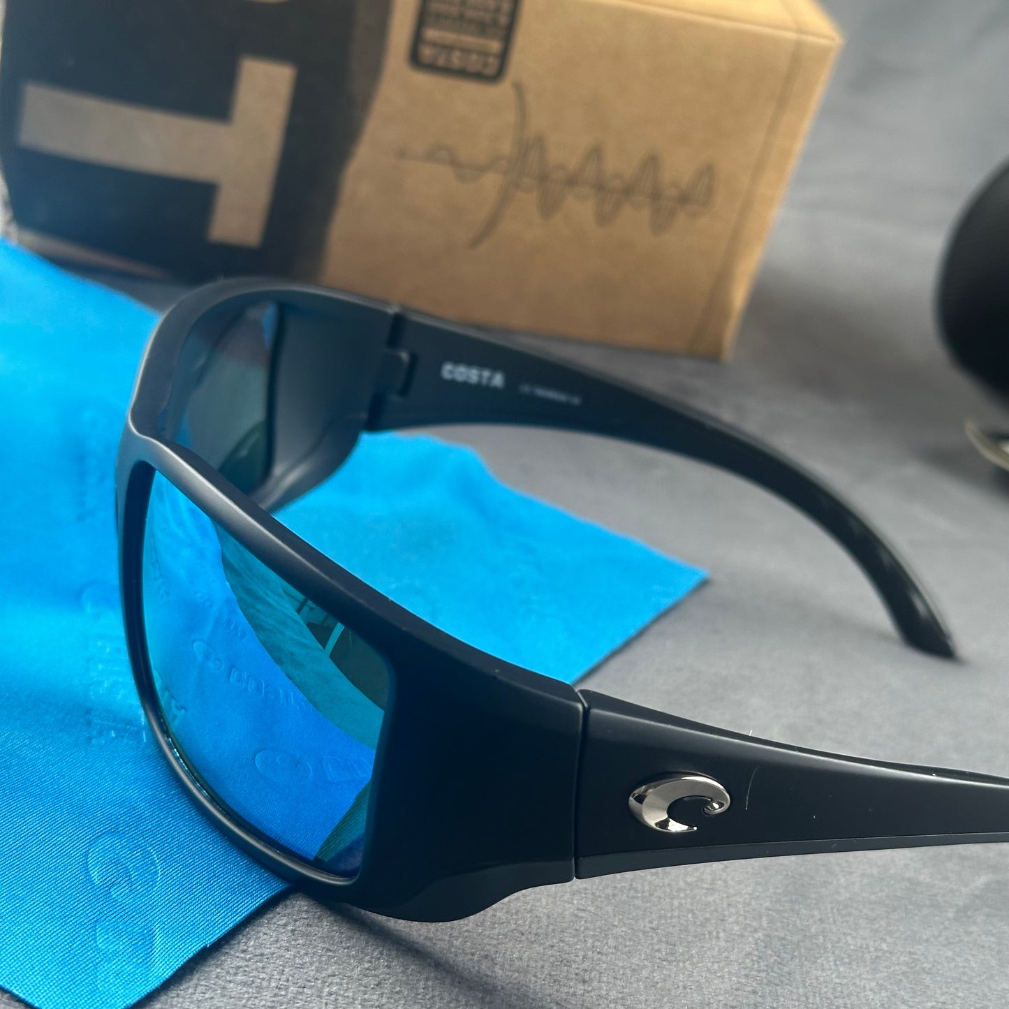 Matte black frame sport sunglasses with blue mirror lenses, including a protective case and cloth.