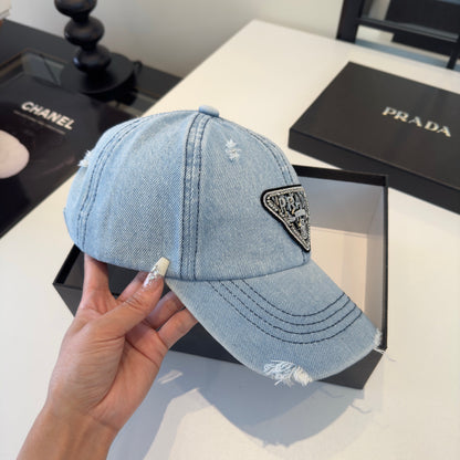 A light blue distressed denim baseball cap with a triangular embroidered patch on the front.