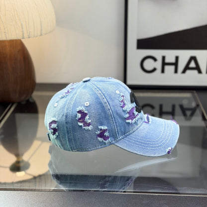 Distressed blue denim baseball cap with frayed detailing and a central stitched logo emblem.
