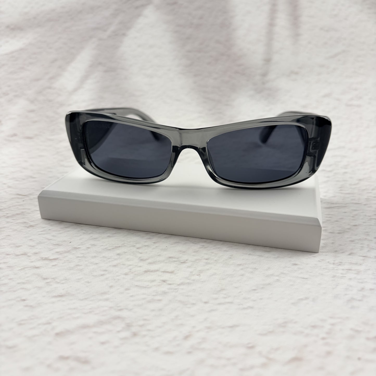 Modern rectangular sunglasses in translucent gray with dark tinted lenses, includes protective case.