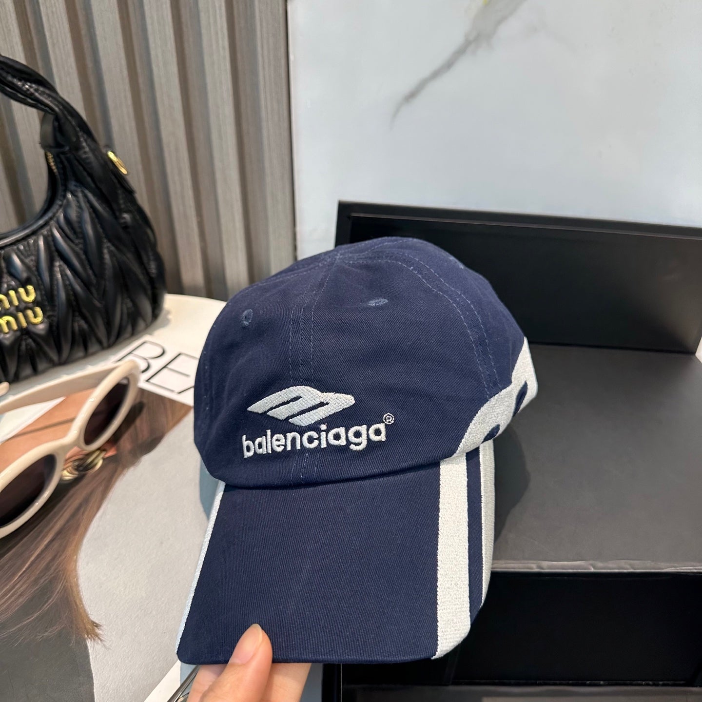 A navy blue cotton baseball cap with white embroidered logo and stripe detail on the side.