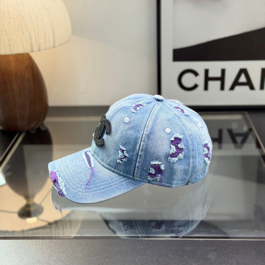 Distressed blue denim baseball cap with frayed detailing and a central stitched logo emblem.