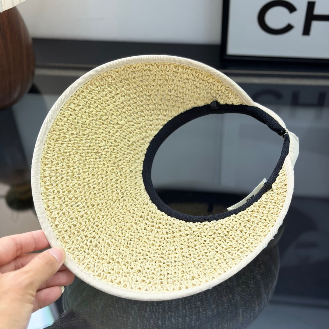 A beige straw sun visor with white polka dot mesh overlay and a gold metallic logo detail.