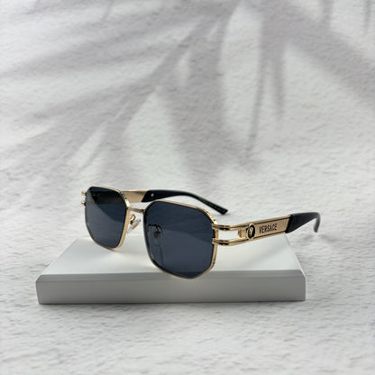 Gold tone metal frame geometric sunglasses with dark lenses on a white display block.