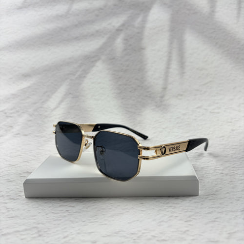 Gold tone metal frame geometric sunglasses with dark lenses on a white display block.