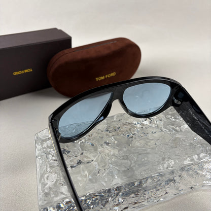 Black acetate oversized aviator sunglasses with blue tinted lenses resting on a clear ice-like block