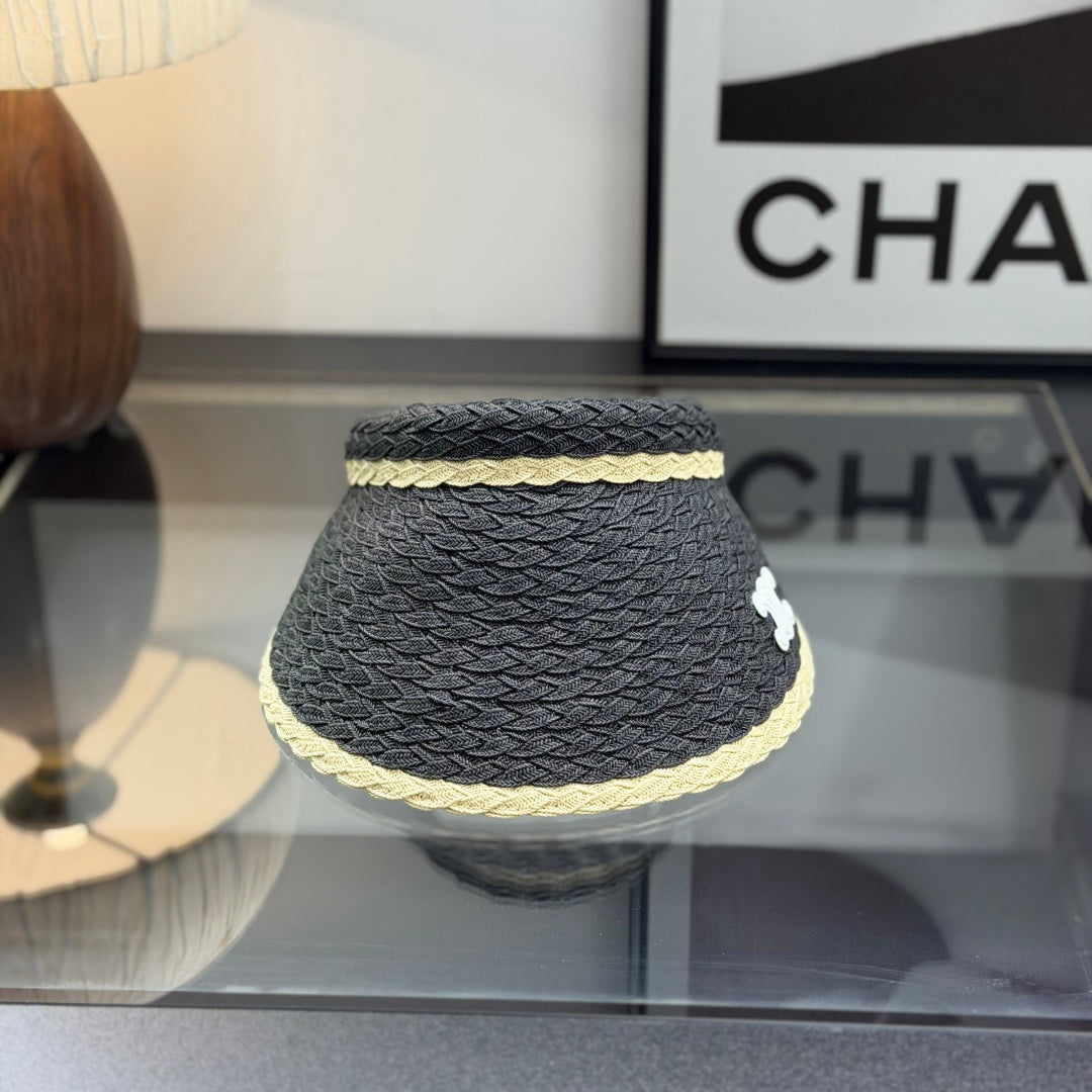 Close-up of a stylish woven straw sun visor with contrast border and white emblem detail.