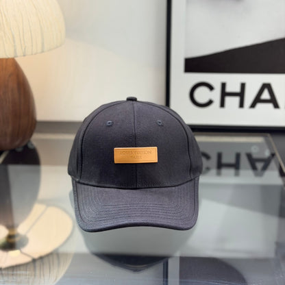 A structured black cotton baseball cap with a rectangular tan faux-leather patch on the front.