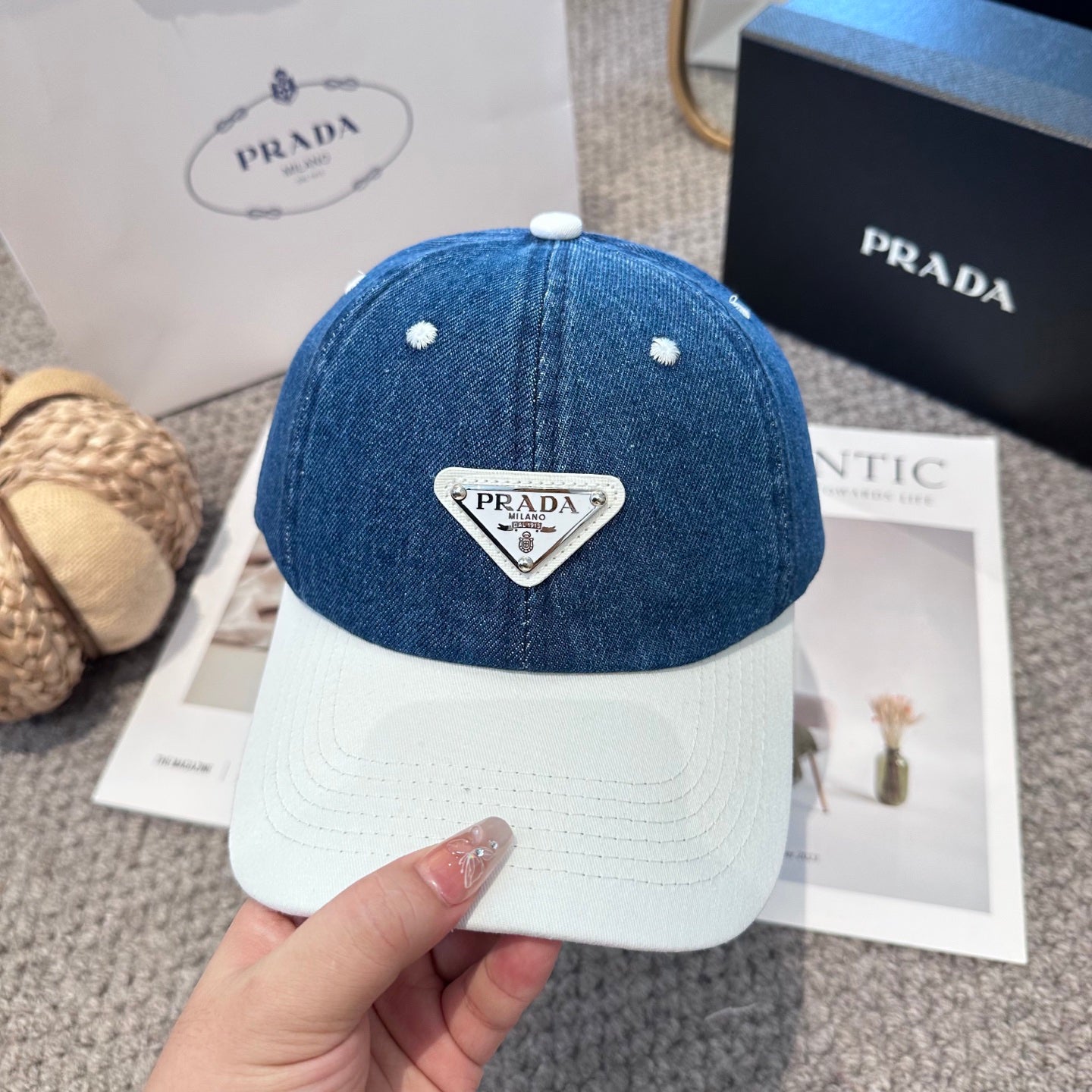 A stylish blue denim baseball cap with a white brim and a triangular metal-look logo patch.