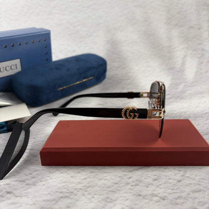 Pilot sunglasses with gold frame accents and dark lenses on a red display case.