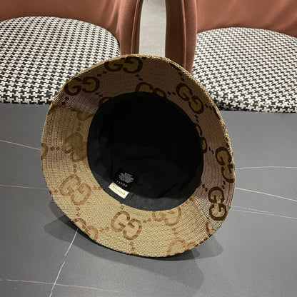A beige canvas bucket hat with an all-over brown monogram pattern and a decorative gold-toned emblem