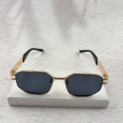 Gold tone metal frame geometric sunglasses with dark lenses on a white display block.