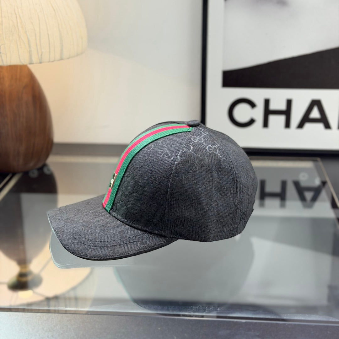 Close-up of a premium black baseball cap with a red and green center stripe and monogram pattern.