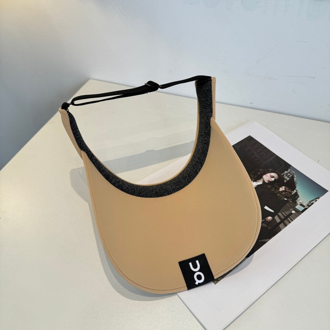 A beige lightweight sport visor with adjustable elastic band, featuring a minimalist logo design.